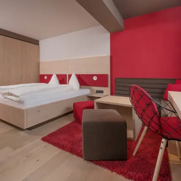 Heuberg Modernes Hotelzimmer mit Doppelbett, Holzmöbeln und roter Akzentwand